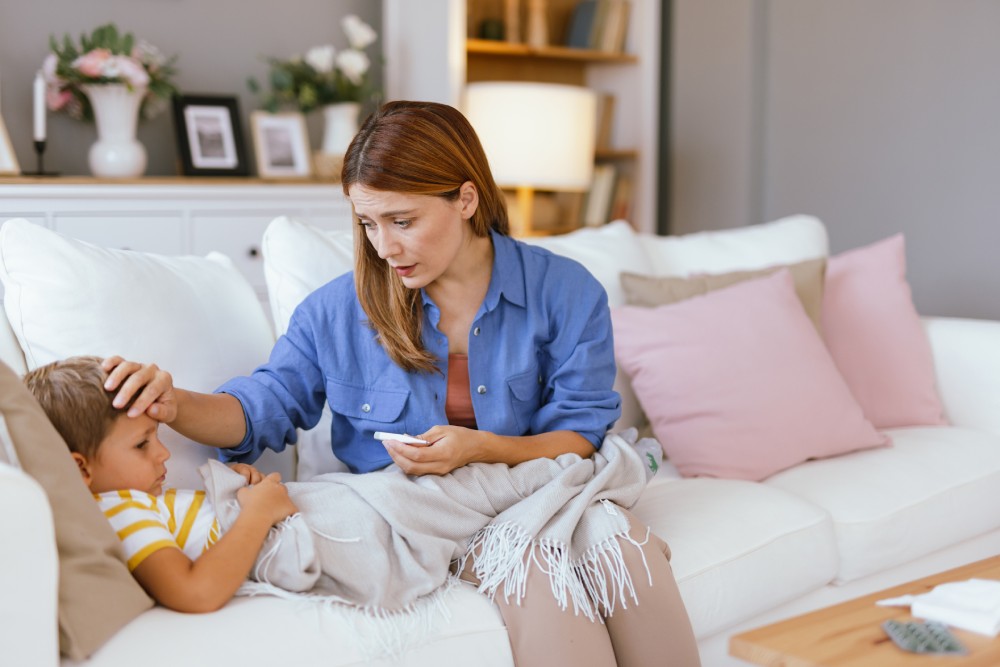 Una madre toca la frente de su hijo para comprobar si tiene fiebre