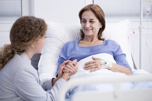 Mujer voluntaria dando la mano a una paciente en el hospital